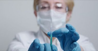 Doktor kameranın önünde şırıngayı iğne için hazırlıyor.