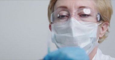 Doktor kameranın önünde şırıngayı iğne için hazırlıyor.