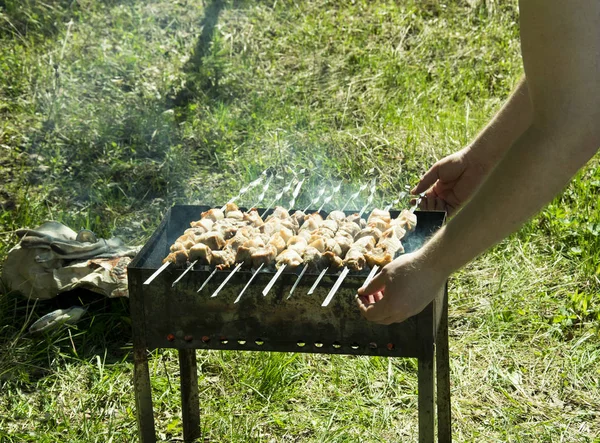 Barbecue on the grill in the summer outdoors, hands turn the ske — Stock Photo, Image