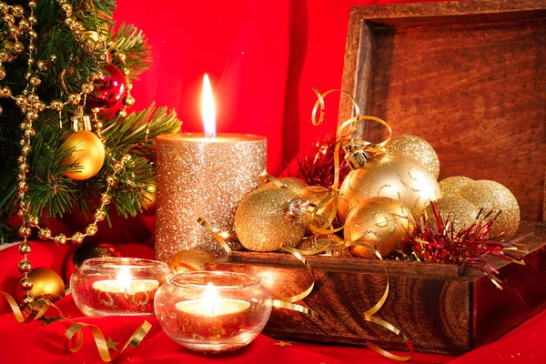 Golden Christmas balls in a wooden box and candles. New Year composition Stock Photo