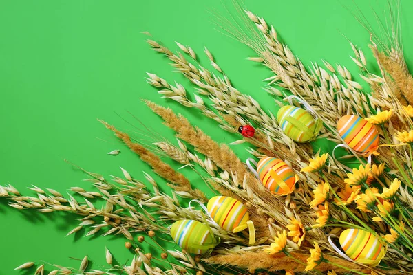 Osterhintergrund. Ziereier und trockenes Gras auf grünem Hintergrund. — Stockfoto