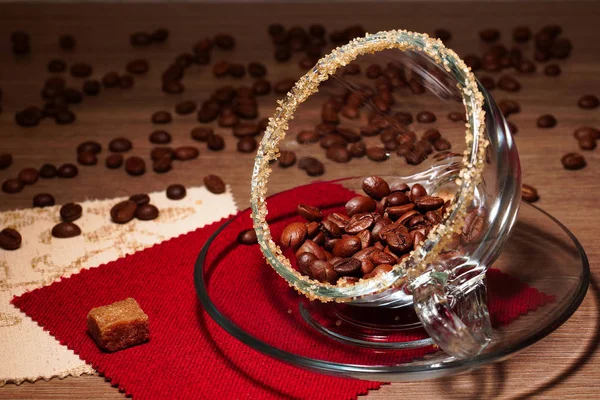 Granos de café en una taza transparente y trozos de azúcar morena — Foto de Stock