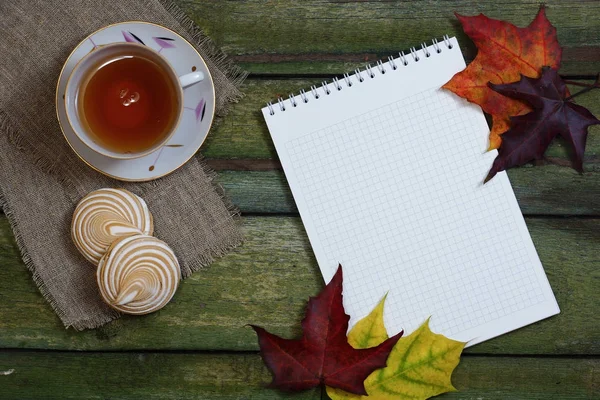 Ahşap bir masa temiz defter ve akçaağaç yaprakları. 