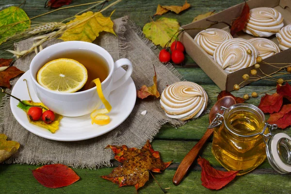 Tea with lemon on a table strewn with autumn foliage. — Stock Photo, Image