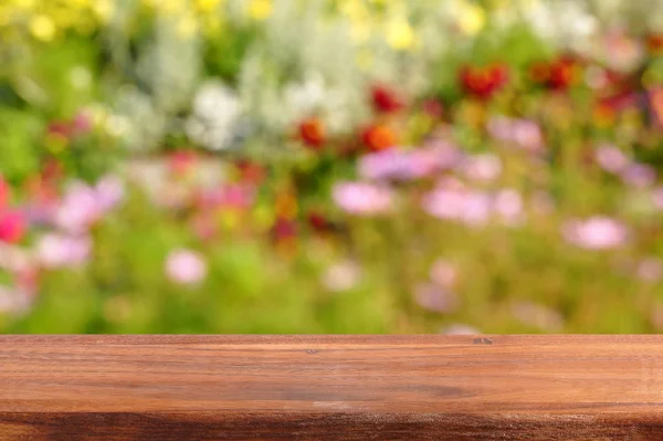 Empty wooden table on the background of a flowering garden. An empty table for presenting your products. Blurred background of a blooming garden.