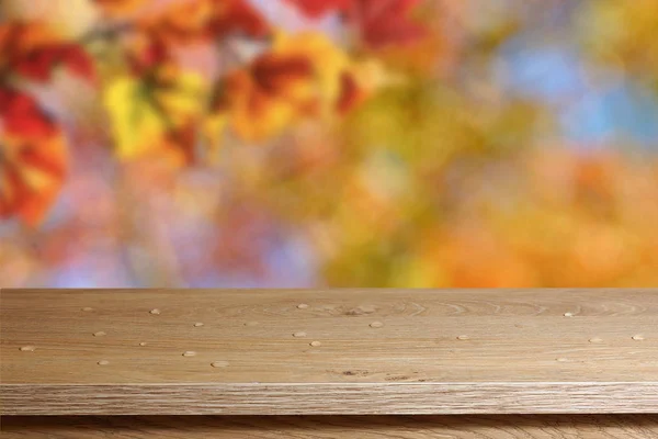 Empty table with water drops on a blurry autumn background. Place for presentation of your goods