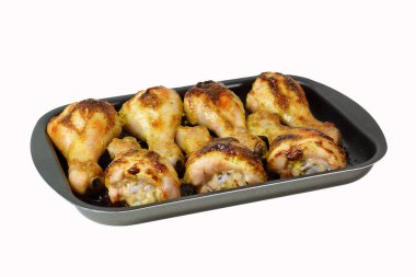 Fırın tepsisinde kızarmış tavuk bacağı. İzole edilmiş