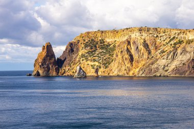 Güneşli yaz gününde St. George Manastırı yakınlarındaki Jasper Sahili 'nden Cape Fiolent Burnu' na manzara. Kayalık kıyısı Karadeniz ve uçurum, Sivastopol, Kırım, Ukrayna. Körfezi çevreleyen manzara dağları.