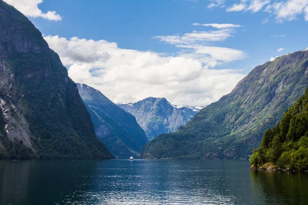 Güneşli bir günde, dağ zirvelerinin yeşil yamaçları, su yüzeyleri ve gökyüzünde tüy bulutları olan manzarası. Neroyfjord - Norveç 'in en dar fiyordu, Gudvangen Flam — Stok fotoğraf