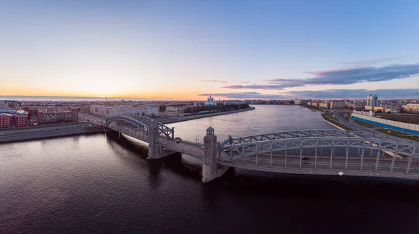 Санкт-Петербург Росія. Повітряний панорамний вид з дрону на міст Петра Великого білої ночі. Більшоктінський міст через річку Неву з вечірнім освітленням міста з водіння автомобілів на автостраді. — стокове фото