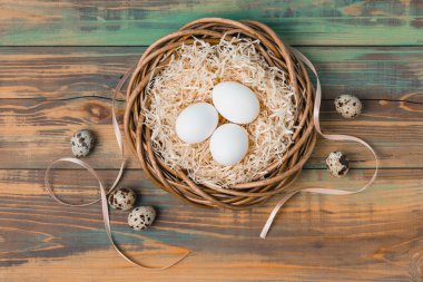 Paskalya yumurta üzerinde ahşap arka plan, üstten görünüm alanı kopyalayın. Paskalya natürmort. Paskalya dekor. Bıldırcın yumurta bir yuvaya boşaltmak metin tebrik için ahşap tablo.