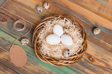 Paskalya yumurta üzerinde ahşap arka plan, üstten görünüm alanı kopyalayın. Paskalya natürmort. Paskalya dekor. Bıldırcın yumurta bir yuvaya boşaltmak metin tebrik için ahşap tablo.
