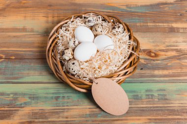 Paskalya yumurta üzerinde ahşap arka plan, üstten görünüm alanı kopyalayın. Paskalya natürmort. Paskalya dekor. Bıldırcın yumurta bir yuvaya boşaltmak metin tebrik için ahşap tablo.