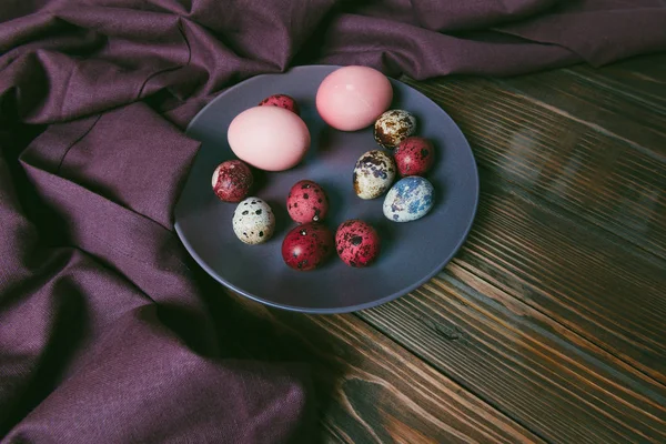 Color Easter eggs with linen cloth on a rustic brown wooden table. Holiday background.