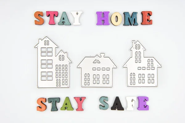 Words Stay home Stay safe made from wooden letters and three metalic houses, concept of self quarantine at home as preventative measure against corona virus Covid 19 outbreak. Staying at home during pandemic