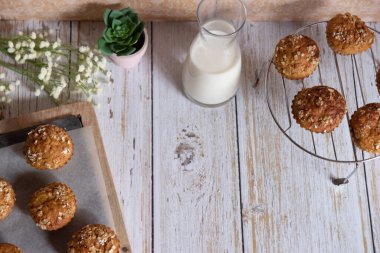 Elma, havuç ve fındıklı tam tahıllı kekler, arka planda kırsal kesim tahtası, sağlıklı vejetaryen yemekleri, süt ürünleri. Üst görünüm.
