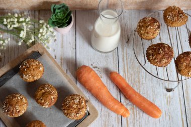 Elma, havuç ve fındıklı tam tahıllı kekler, arka planda kırsal kesim tahtası, sağlıklı vejetaryen yemekleri, süt ürünleri. Üst görünüm.