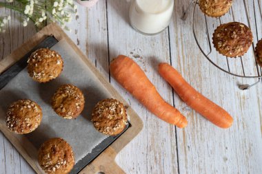 Elma, havuç ve fındıklı tam tahıllı kekler, arka planda kırsal kesim tahtası, sağlıklı vejetaryen yemekleri, süt ürünleri. Üst görünüm.