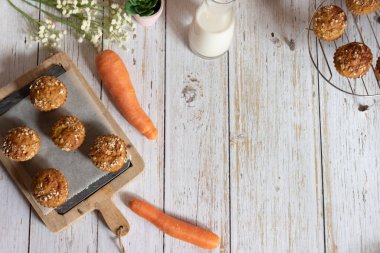 Elma, havuç ve fındıklı tam tahıllı kekler, arka planda kırsal kesim tahtası, sağlıklı vejetaryen yemekleri, süt ürünleri. Üst görünüm.