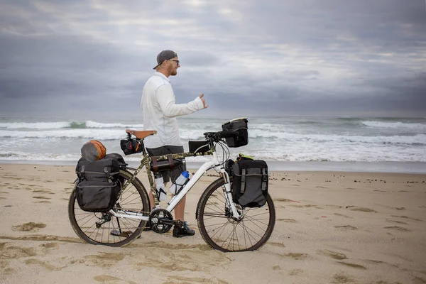 Giovane impacchettatore ciclistico mand raggiunge la spiaggia Immagine Stock