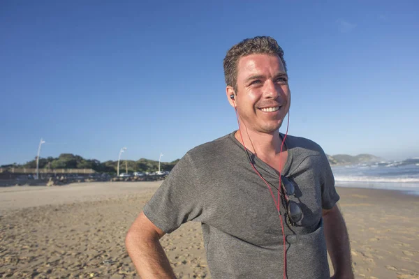 Homme avec écouteurs par plage — Photo