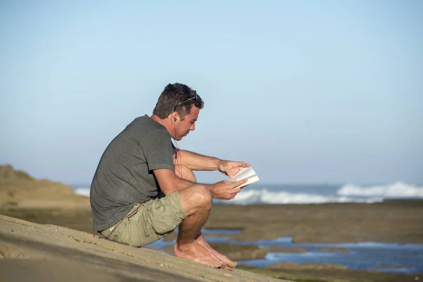 Man by Oceand leyendo y escuchando música — Foto de Stock