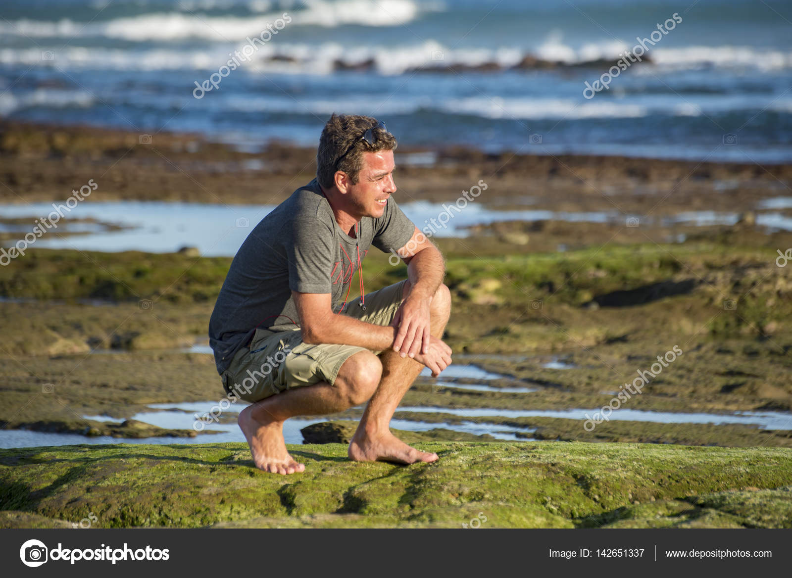 Man on haunches by rockpool Stock Photo by JFJacobsz 142651337