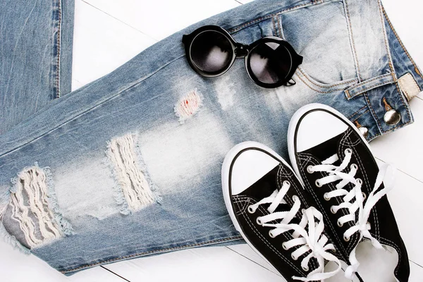 Jeans na moda com óculos de sol em um fundo branco — Fotografia de Stock