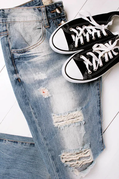 Jeans na moda com sapatilhas em um fundo branco — Fotografia de Stock