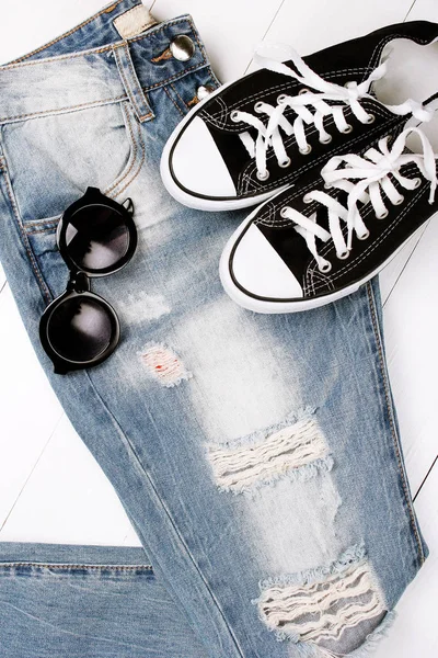 Jeans na moda com sapatilhas em um fundo branco — Fotografia de Stock