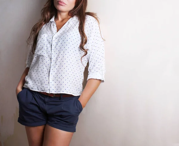 Mode. Eine junge Frau in modischer Bluse und Shorts steht in der Nähe einer beigen Wand — Stockfoto