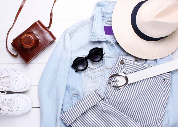Moda. Jaqueta jeans, calças de moda, chapéu, câmera velha e óculos de sol em um fundo branco — Fotografia de Stock