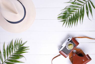 Eski fotoğraf makinesi, palmiye dalı ve beyaz arka plan üzerinde hasır şapka
