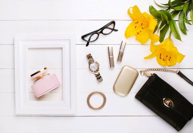 Perfume in a white frame, lily flowers, lipstick and glasses on a white background clipart