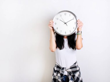 Beyaz bir t-shirt beyaz bir arka plan üzerinde bir saat tutan genç kız