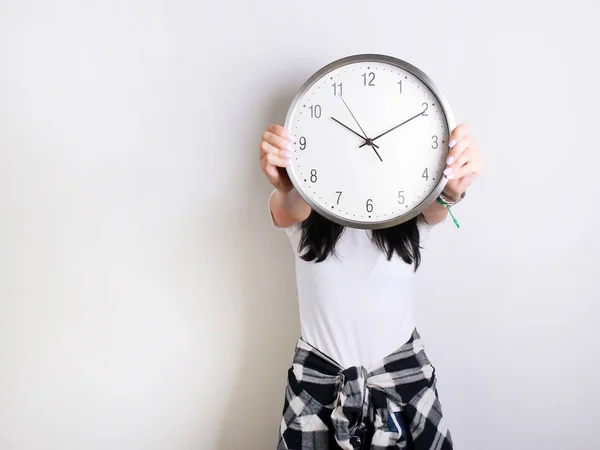 Beyaz bir t-shirt beyaz bir arka plan üzerinde bir saat tutan genç kız — Stok fotoğraf