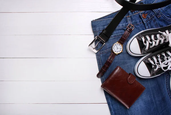 Vaqueros de moda, reloj, bolso, cinturón y zapatillas de deporte sobre un fondo blanco —  Fotos de Stock