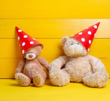 Sarı bir arka plan üzerinde kırmızı bere kutlama bir ayı oturuyor