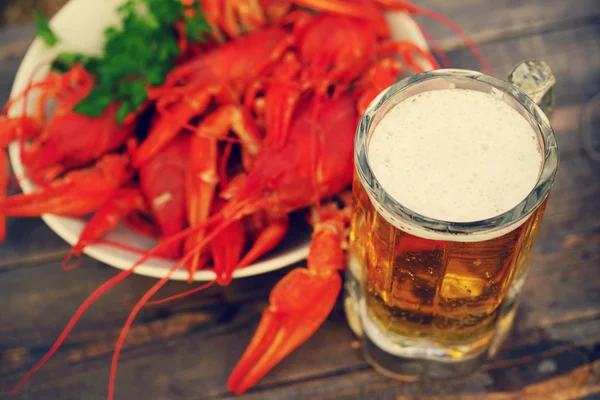 Copo de cerveja e um lagostins fervidos em uma chapa — Fotografia de Stock