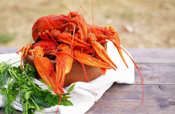 Gekookte crawfishes in een ronde houten plaat op een houten achtergrond — Stockfoto