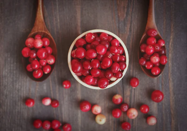 Fresh red forest cranberry in wooden round bowl with a wooden spoons — Stock Photo, Image
