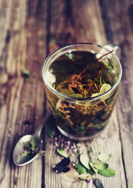 Herbal tea in a transparent glass mug and forest herbs