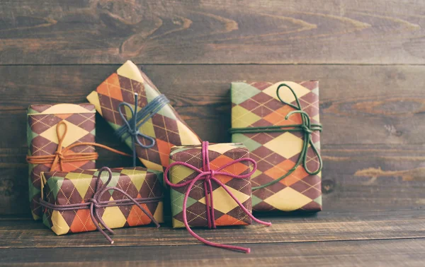 Festive boxes in colourful paper on a wooden background in vintage color. Holidays gift background — Stock Photo, Image