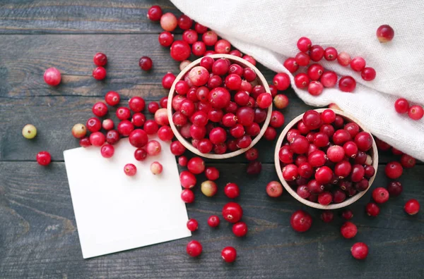 Cranberry suculento fresco em tigelas redondas de madeira e cartão branco com a inscrição em uma mesa — Fotografia de Stock