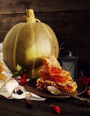 Kabak, peteğin bir plaka ve şamdan sonbahar yaprakları ile ahşap bir yüzey üzerinde bal.