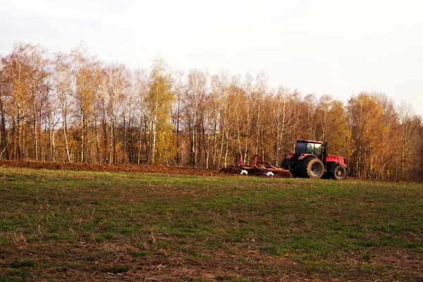 Trekker in het veld biedt de aarde in de herfst — Stockfoto