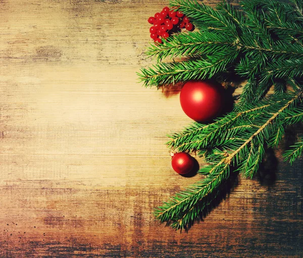 Natural fir branch and a New Year's fir tree toys on a wooden background. New Year's background — Stock Photo, Image