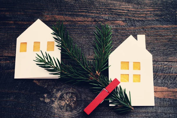 Christmas lodges from white paper with a fir-tree branch on a wooden background. — Stock Photo, Image