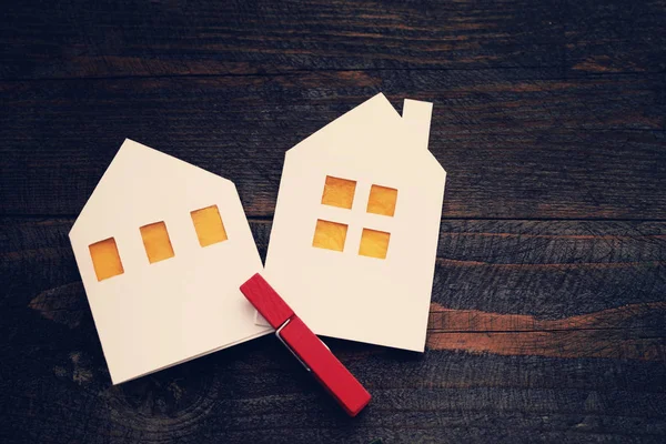 Two lodges from white paper on a wooden background. Symbol of the house, family, cosiness. — Stok Foto