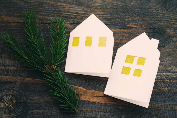 Christmas lodges from white paper with a fir-tree branch on a wooden background. — Stock Photo, Image